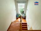 Staircase with wooden steps leading to a window with plants outside