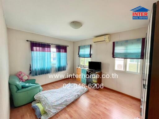 Bedroom with wooden floor, windows with curtains, air conditioning, TV, and bed