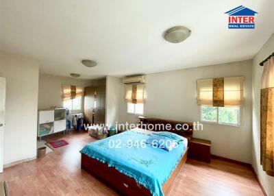 Spacious bedroom with a wooden floor, large windows, and a bed with blue bedding.