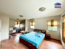 Spacious bedroom with a wooden floor, large windows, and a bed with blue bedding.