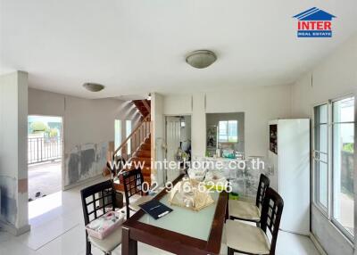 Modern dining area adjacent to a staircase and large windows