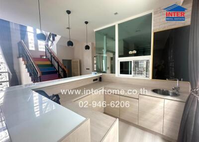 Modern kitchen with island counter and colorful staircase