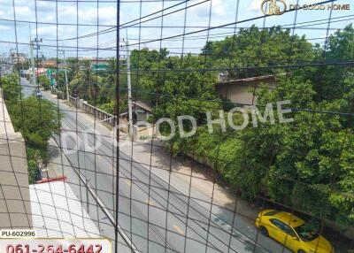 Balcony view overlooking a road with greenery and a yellow taxi