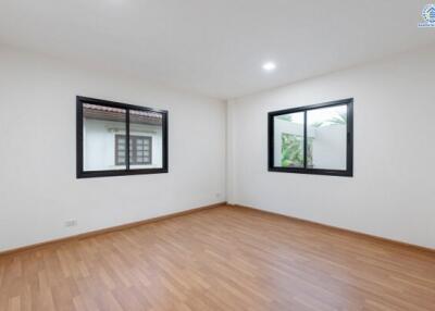 Spacious and bright empty bedroom with wooden floor and large windows