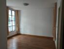 Empty bedroom with wooden flooring and curtains