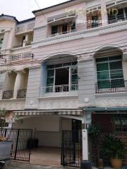 Front view of a multi-story residential building with gated entry and balconies