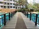 Walkway over swimming pool with palm trees and building in the background