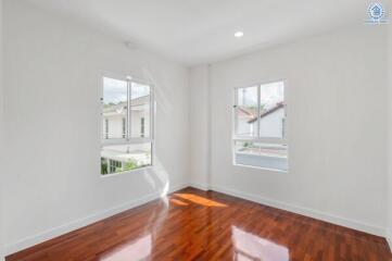 Empty bedroom with hardwood floors and large windows