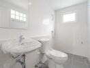 Clean and modern bathroom with white tiles, a sink, toilet, and shower