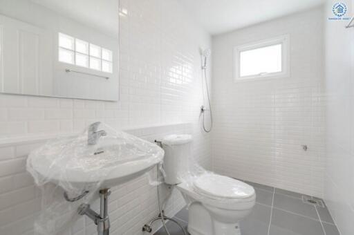 Clean and modern bathroom with white tiles, a sink, toilet, and shower