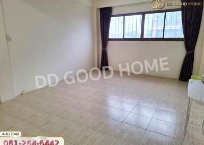 Empty living room with tiled floor, large window, and dark curtains.