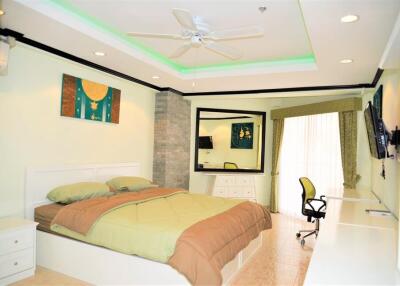 Spacious bedroom with modern decor, a large bed, desk, and seating area