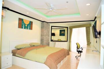 Spacious bedroom with modern decor, a large bed, desk, and seating area