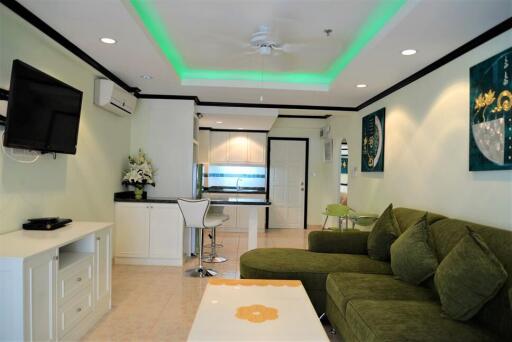 Modern living room with green couch, ceiling fan, and wall-mounted TV