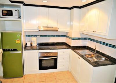 Modern kitchen with white cabinets, green fridge, and appliances