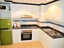 Modern kitchen with white cabinets, green fridge, and appliances