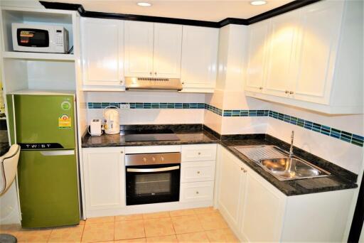 Modern kitchen with white cabinets, green fridge, and appliances