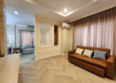 Modern living room with a brown sofa and light wood flooring