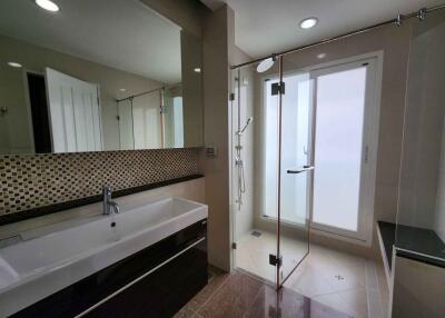 Modern bathroom with large sink, mirror, and glass shower enclosure