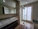 Modern bathroom with large sink, mirror, and glass shower enclosure