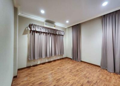 spacious bedroom with wooden flooring and curtains