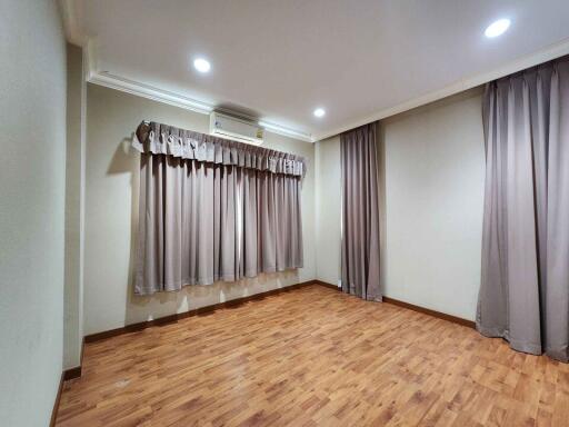 spacious bedroom with wooden flooring and curtains