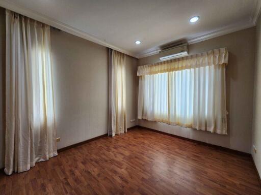 Empty bedroom with wooden flooring and curtains