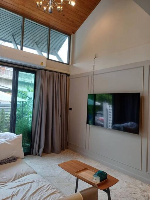 Modern living room with high ceiling, large window and wall-mounted TV