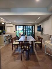 spacious dining area with table and chairs, adjacent to a well-lit space