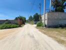 Dirt road alongside a fenced property