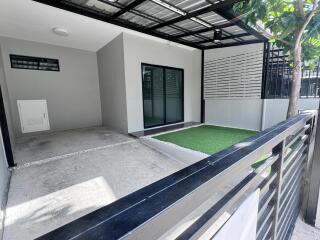 Covered outdoor space with artificial grass and concrete area