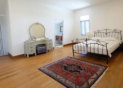 Spacious bedroom with hardwood floor, iron bed frame, and a vintage dresser