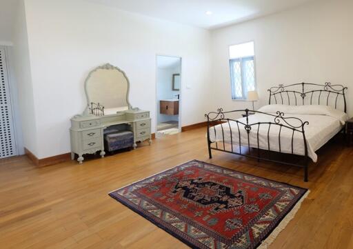 Spacious bedroom with hardwood floor, iron bed frame, and a vintage dresser