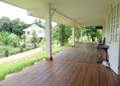 Spacious veranda with wooden flooring and a view of a lush garden