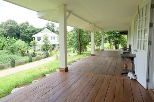 Spacious veranda with wooden flooring and a view of a lush garden