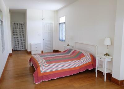 A spacious bedroom with a colorful bedspread and wooden flooring.