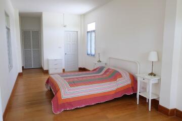 A spacious bedroom with a colorful bedspread and wooden flooring.