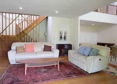 Spacious living room with stairs, couches, and a wooden coffee table