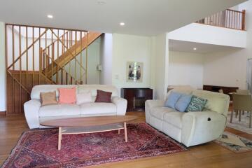 Spacious living room with stairs, couches, and a wooden coffee table