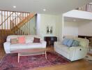 Spacious living room with stairs, couches, and a wooden coffee table