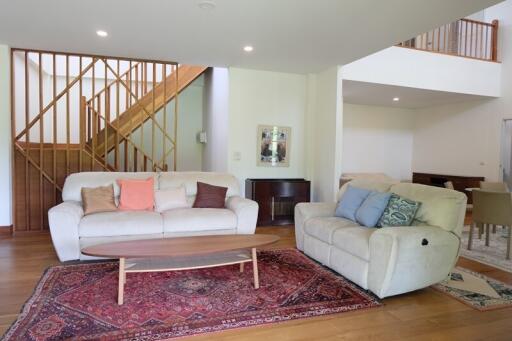 Spacious living room with stairs, couches, and a wooden coffee table