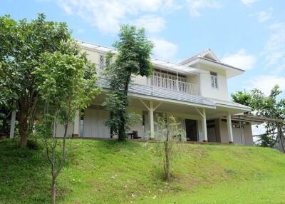 Exterior view of a two-story house with trees and greenery