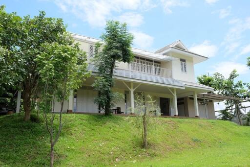 Exterior view of a two-story house with trees and greenery