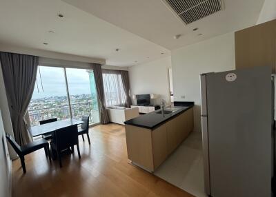 Open-plan living area with kitchen, dining table, and city view from the balcony