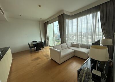 Bright living room with large windows, sofa, dining table, and city view