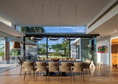 Modern dining room with large windows, a long table, and stylish lighting