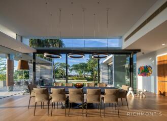 Modern dining room with large windows, a long table, and stylish lighting