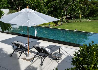 Outdoor pool area with lounge chairs and umbrella