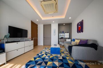 Modern living room with grey sofa, geometric rug, and entertainment center