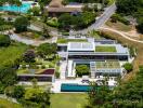 Aerial view of a modern luxury property with multiple swimming pools and greenery.